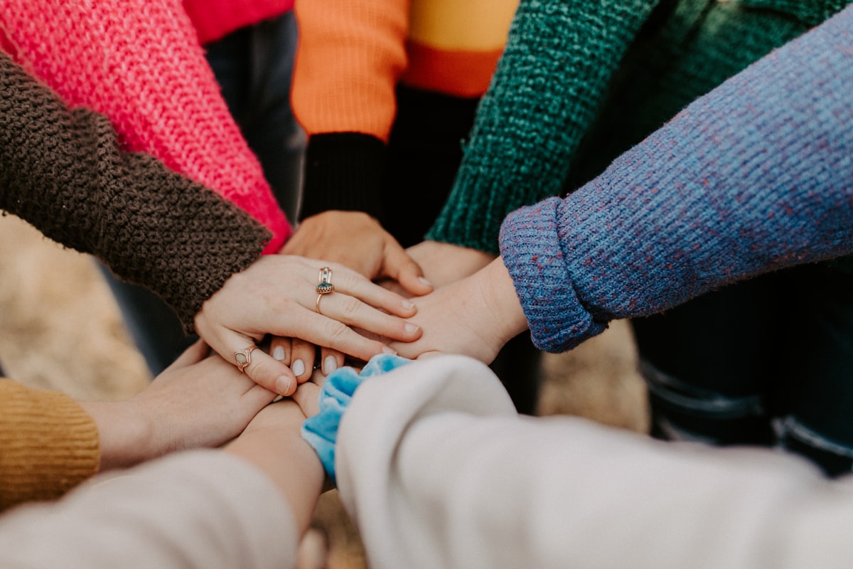 A group of people stacking their hands together, symbolizing generosity and community