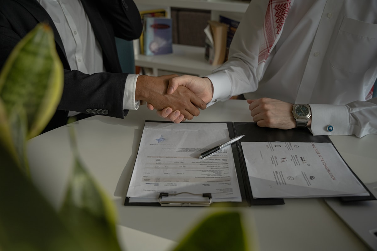Two business partners shaking hands over a signed agreement, symbolizing trust